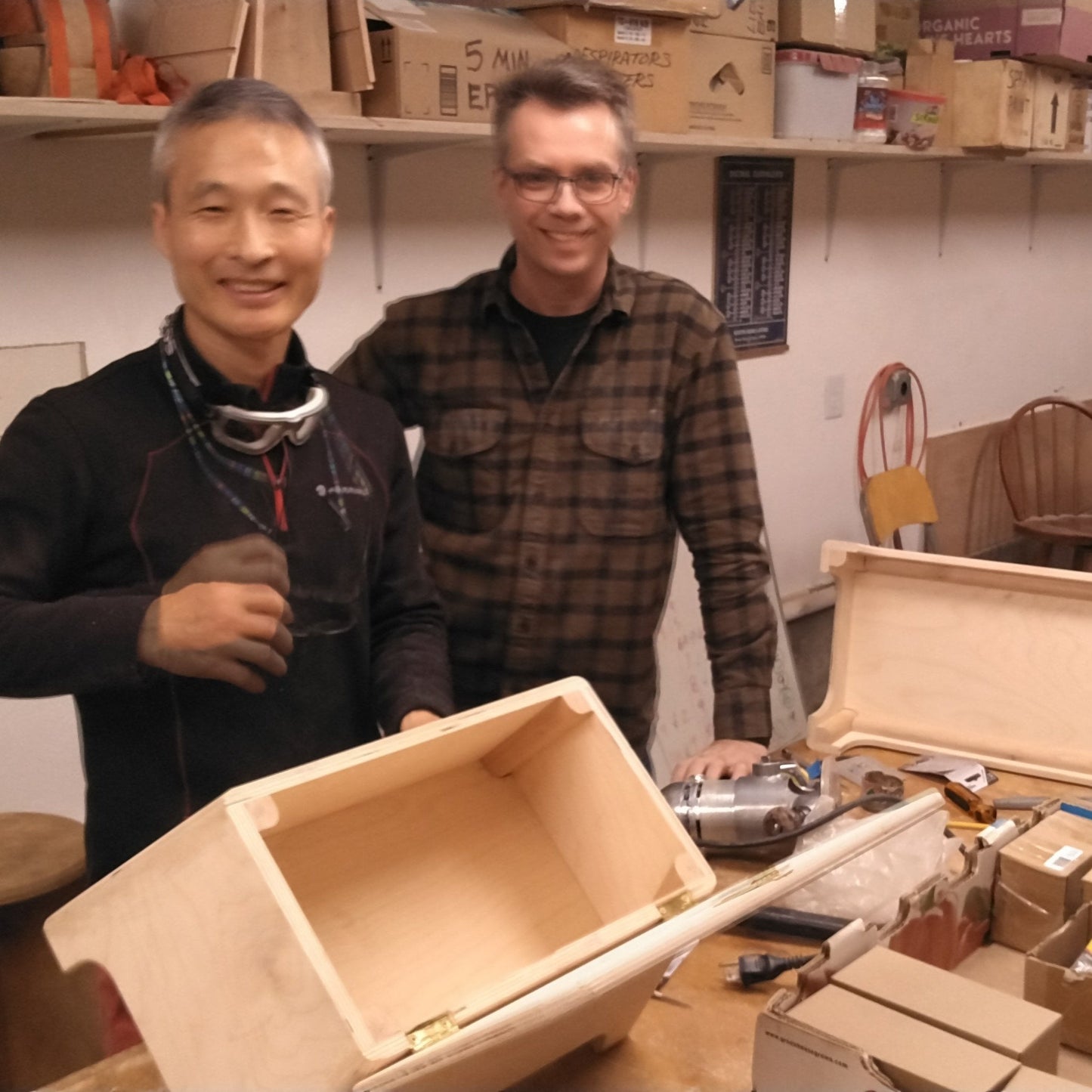 2 men showing their woodworking stool project in a classroom.